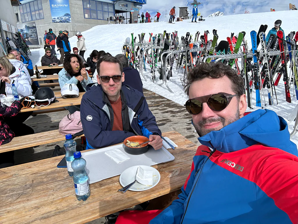 Peptone team members sharing lunch at an outdoor table beside the ski slopes