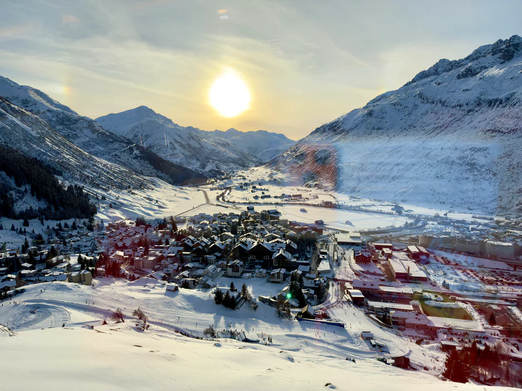 A snow-covered Andermatt valley and village beneath the low winter sun
