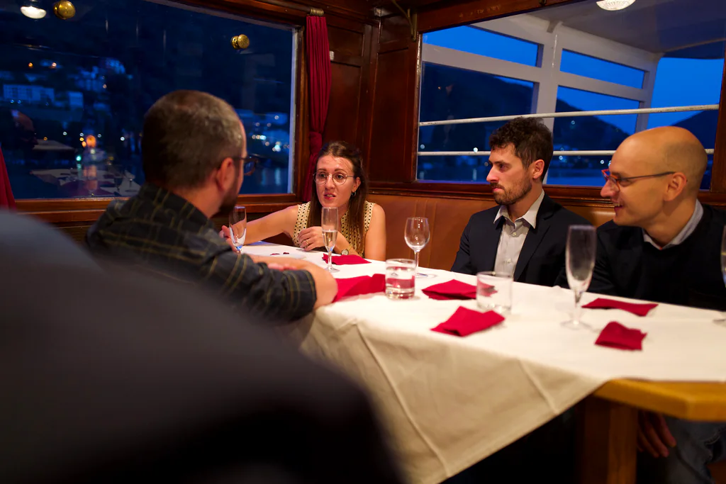 Peptone team members in conversation over dinner aboard a Lake Lugano boat
