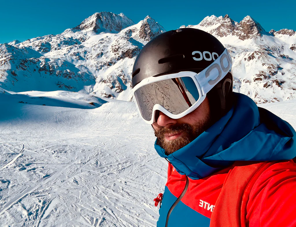 A Peptone team member in ski goggles against bright Alpine peaks