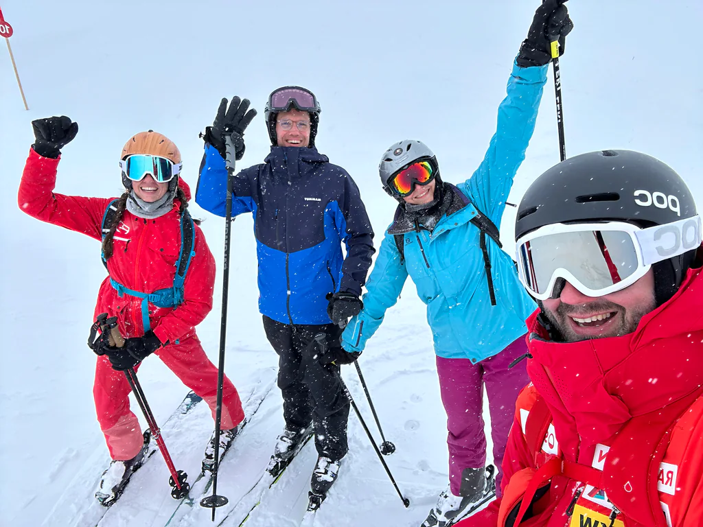 Four Peptone team members waving during a snowy ski day